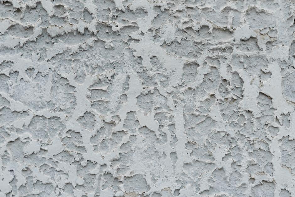 Closeup of rough textured cracked surface of aged stucco wall as abstract background