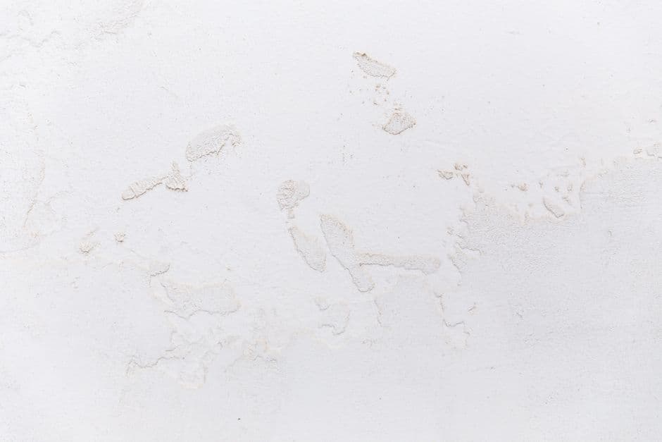 Abstract texture of white surface of concrete wall covered with cracked stucco